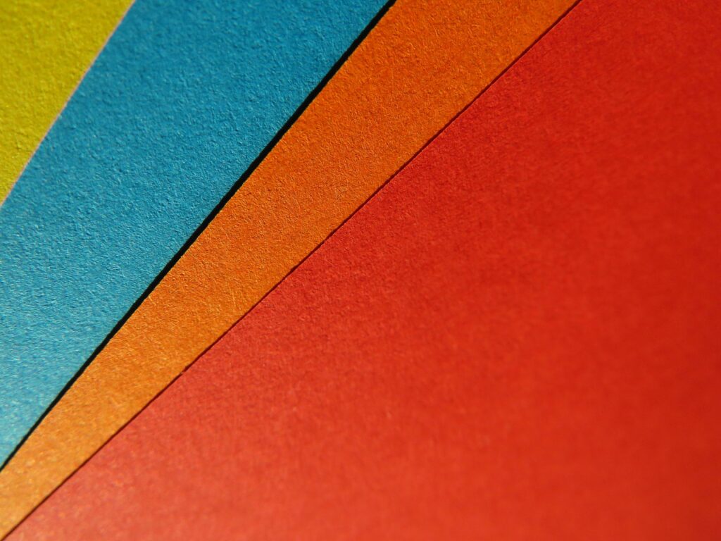 Close-up of vibrant, colorful paper sheets arranged in a geometric pattern, perfect for artistic backgrounds.