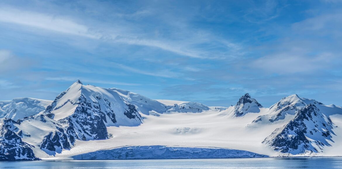 Breathtaking view of rugged snowy mountains under a clear blue sky in Antarctica.