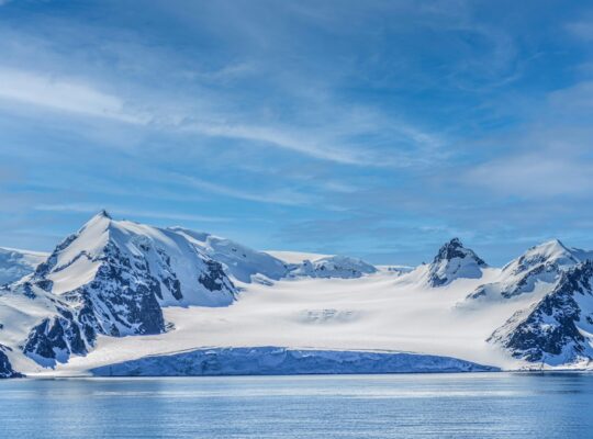 Breathtaking view of rugged snowy mountains under a clear blue sky in Antarctica.